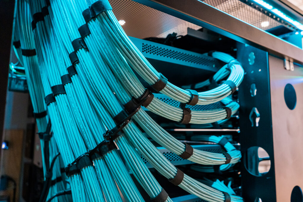 Over 10 bundles of blue cables hanging from the ceiling and wrapping into hardware