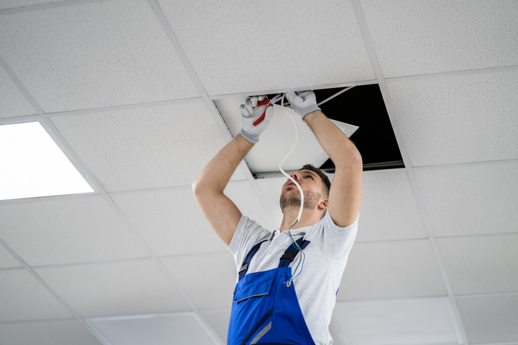 Electrician on a stepladder installs lighting into the ceiling