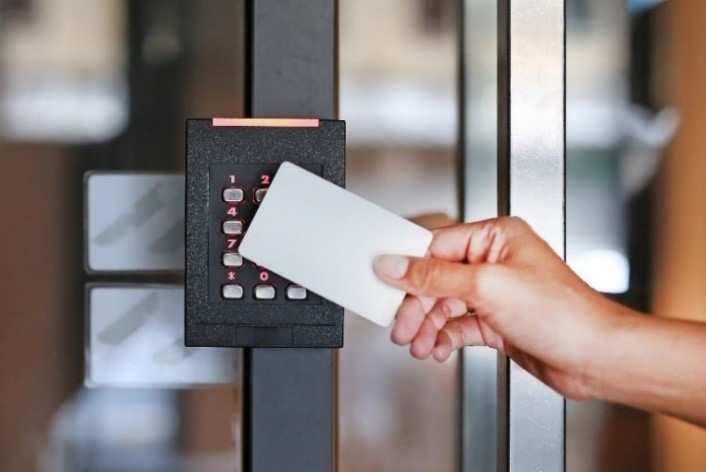 Person swiping a white card on a black security keypad